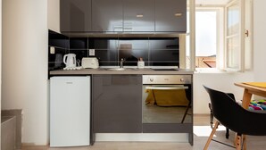 A compact kitchen with a dishwasher, a small refrigerator, and a microwave. There is a window providing natural light and a view of the outside. - Dominium Old City Suite (Dubrovnik)