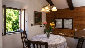 Ein gemütlicher Essbereich mit einem runden Tisch, Holzstühlen, einer weißen Tischdecke aus Spitze, einer Vase mit Blumen und einer Kandelaber.