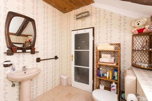 A bathroom with a sink, mirror, toilet, and shelves with toiletries. - Gina Apartment (Dubrovnik)