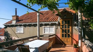 Eine Terrasse mit Tisch und Stühlen, eine Holztür und ein Ziegeldach.