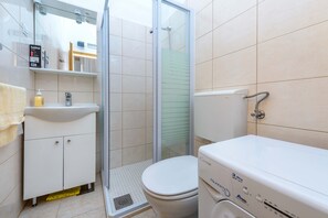 A bathroom with a toilet, sink, and shower. - Kike's Apartment (Dubrovnik)