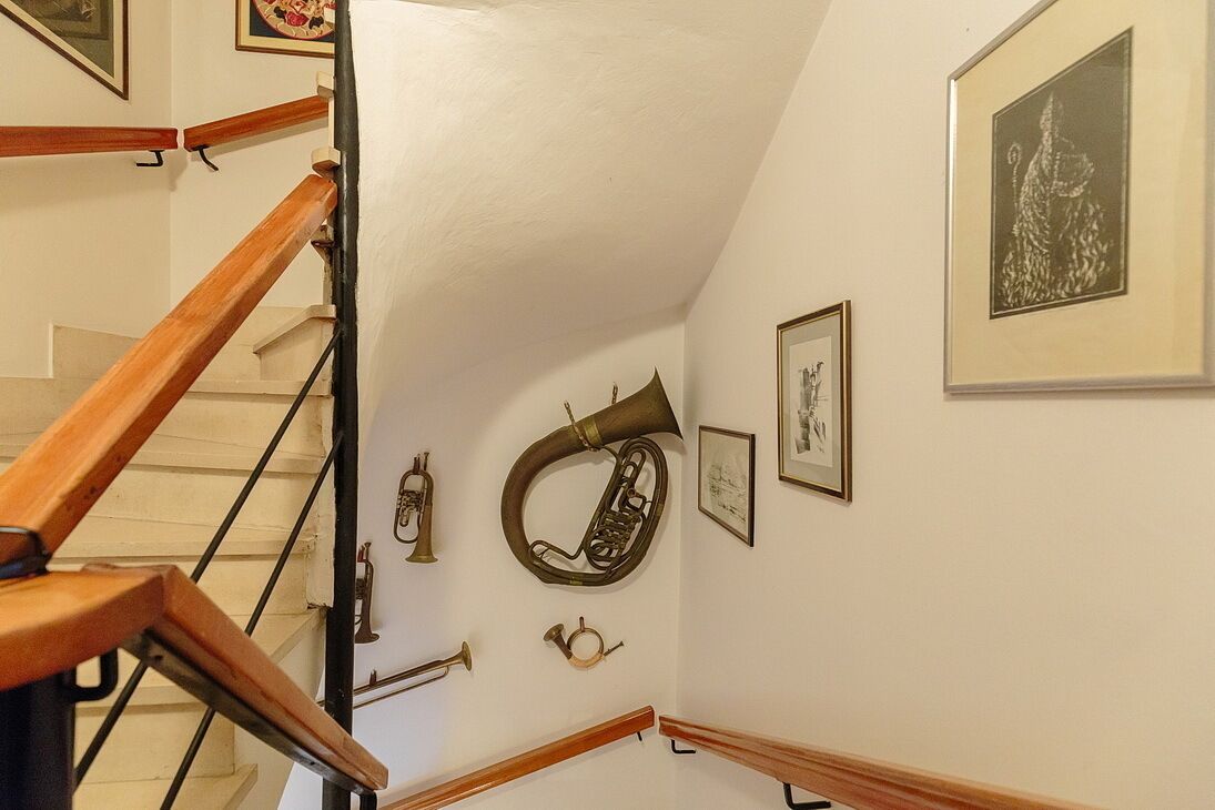 A staircase with wooden handrails and brass musical instruments mounted on the wall.
