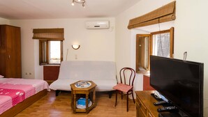 A bedroom with a bed, a sofa, a TV, and a small table with a remote control. - Studios Lončarica (Dubrovnik)