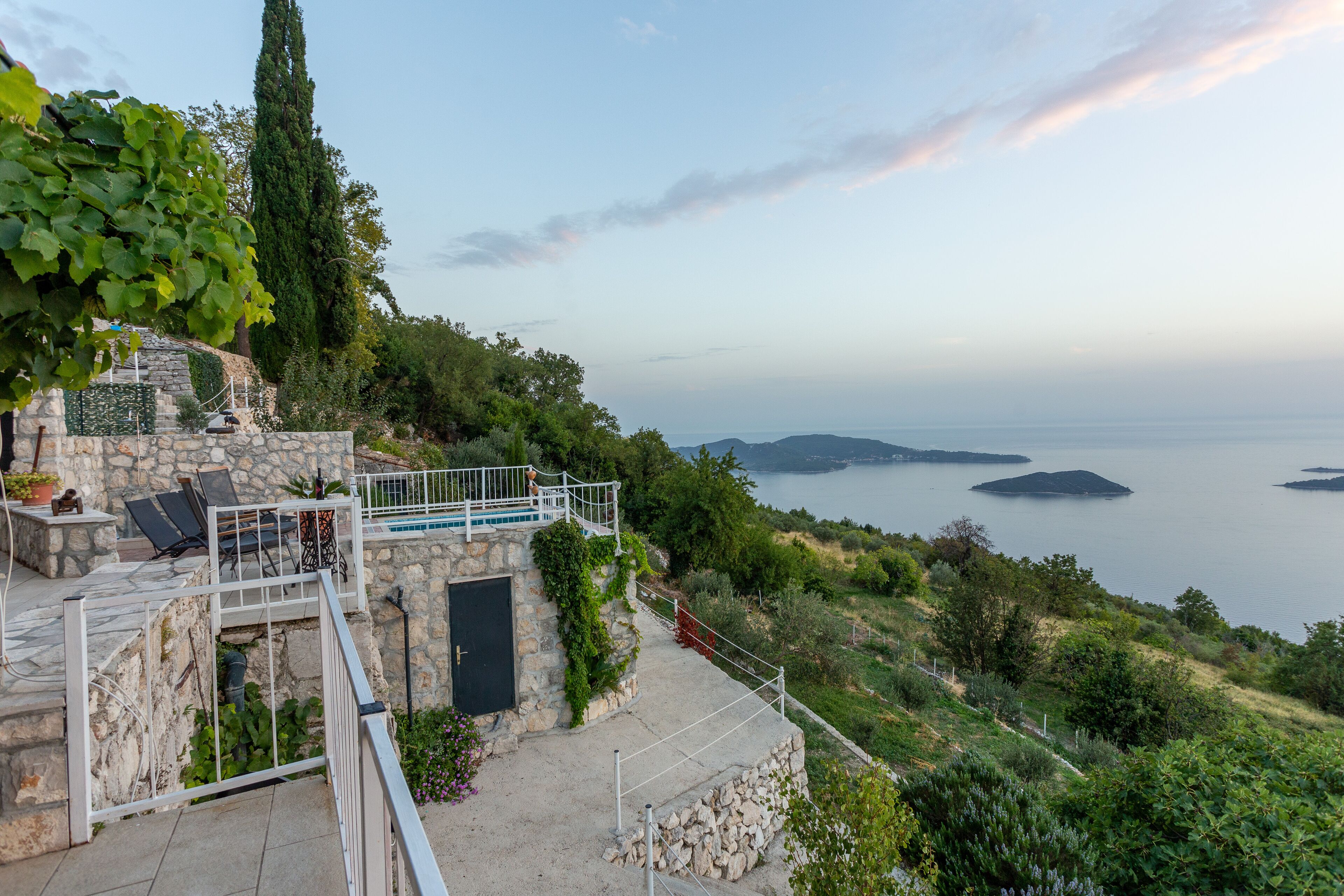 A stone building with a balcony overlooking a body of water and hills.