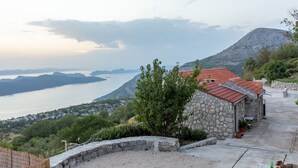 Ein Gebäude aus Stein mit rotem Dach, einer Schotterauffahrt und Blick auf einen See und Berge.