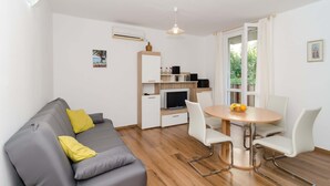 A modern living room with a grey sofa, white chairs, a wooden dining table, and a TV. - Vintage Dream Peyton Apartment (Dubrovnik)