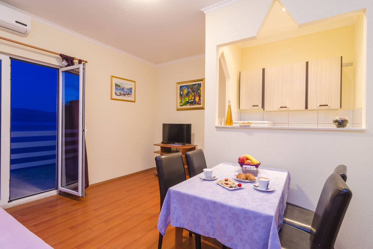 A dining area with a table set for two, a television, and artwork on the walls.