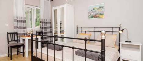 Een slaapkamer met een bed, nachtkastje, stoel en een bureau met een stoel.
