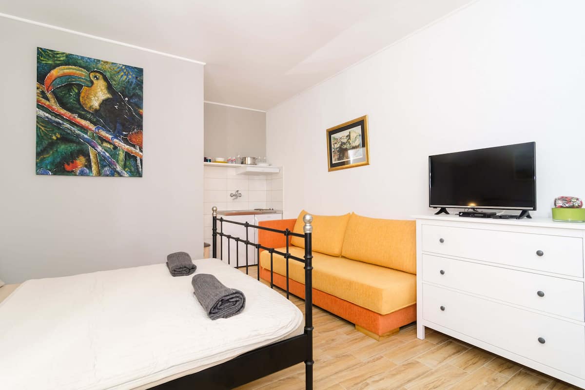 Ein Schlafzimmer mit Bett, Sofa, Fernseher und einem Gemälde an der Wand.