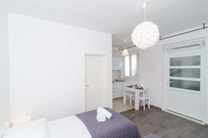 A modern bedroom with a bed, a desk, and a dining area.
