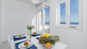 A dining area with a white table, blue placemats, and a variety of fruits and pastries. - Cin & Co Central Apartments (Dubrovnik)