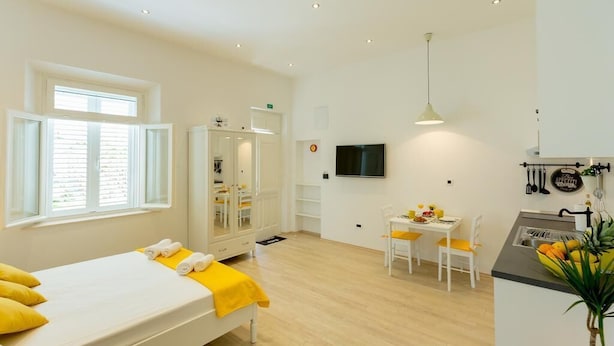 Quarto com cama, escrivaninha e pequeno espaço de cozinha.