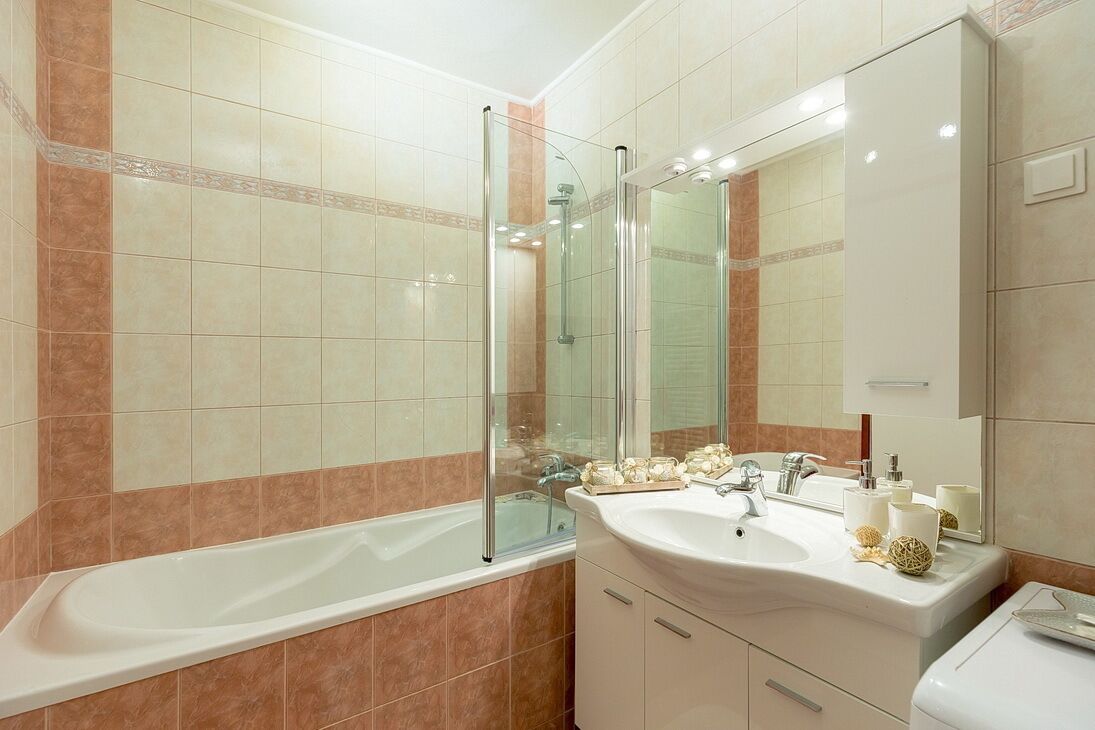 A modern bathroom with a glass-enclosed shower, a white sink, and a large mirror.