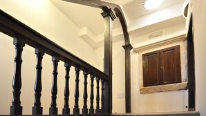 A staircase with dark balusters and a wooden handrail, leading to a room with a window and a door. - Studio Inn (Dubrovnik)
