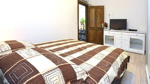 A bedroom with a bed, a TV, a desk, and a wardrobe. - Studio Inn (Dubrovnik)