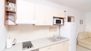 A modern kitchen with white cabinets, a microwave, and a sink. - Apartments Feral (Mljet)