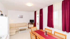 A compact living space with a sofa, a dining table, and a television. - Apartments Feral (Mljet)