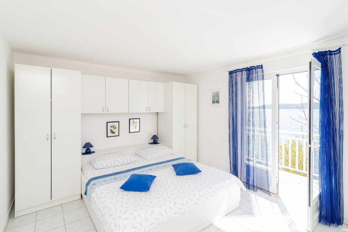 A bedroom with a bed, white wardrobe, and a view of the outdoors.