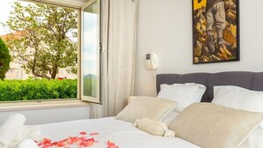 Une chambre d’hôtel avec un lit, un tableau, un téléphone et une fenêtre avec des rideaux.