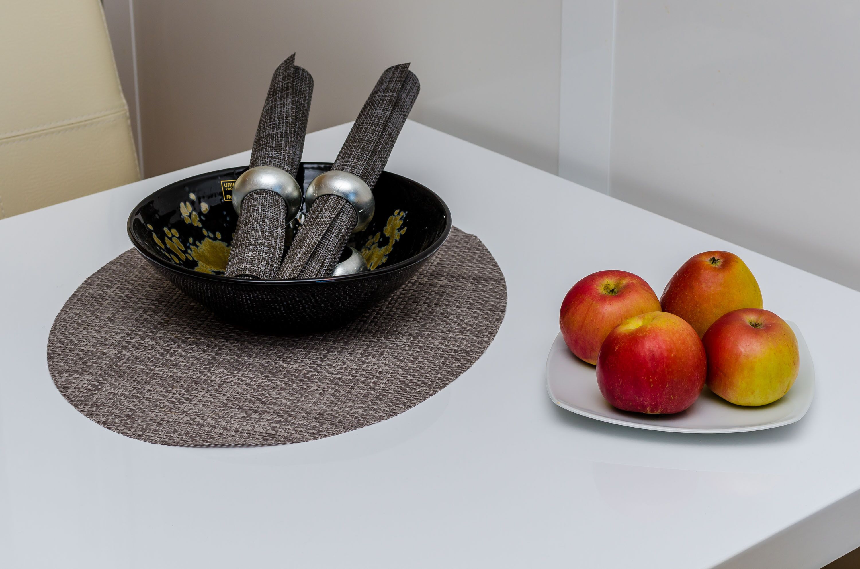 Un bol con utensilios y manzanas sobre una mesa.