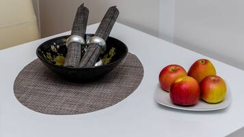 Un bol con utensilios y manzanas sobre una mesa.