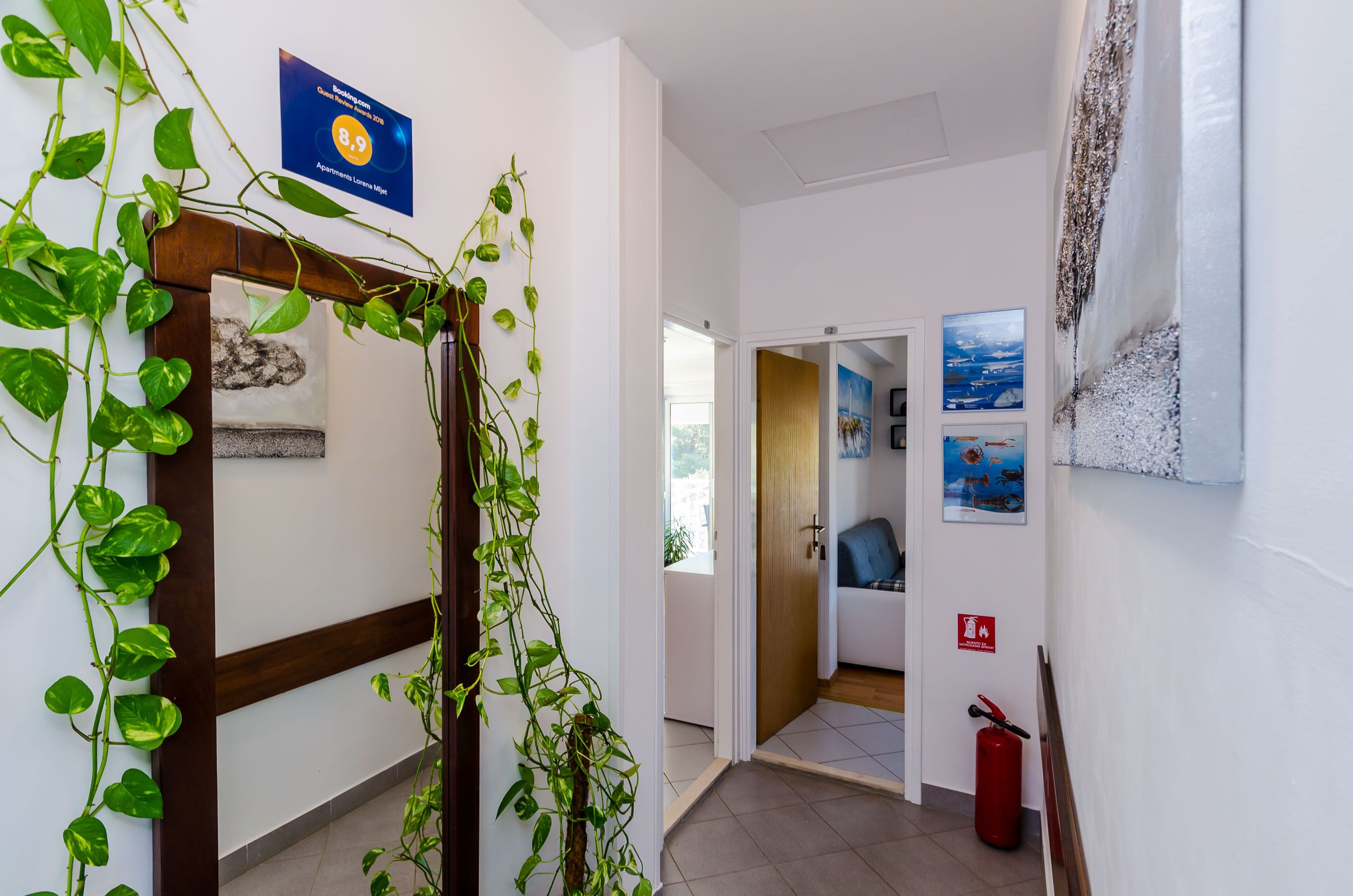 Un couloir avec une porte en bois, un extincteur et un panneau sur le mur.