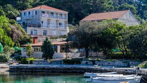 A coastal building with multiple balconies, a stone facade, and a clear view of the marina with boats.