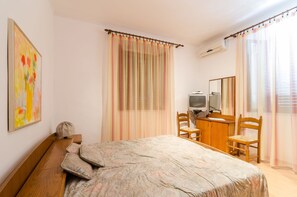 A bedroom with a bed, a desk, a chair, a television, and a mirror. - Rooms Mozara (Dubrovnik)