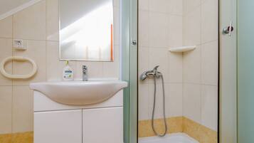 A bathroom with a sink, mirror, and shower.
