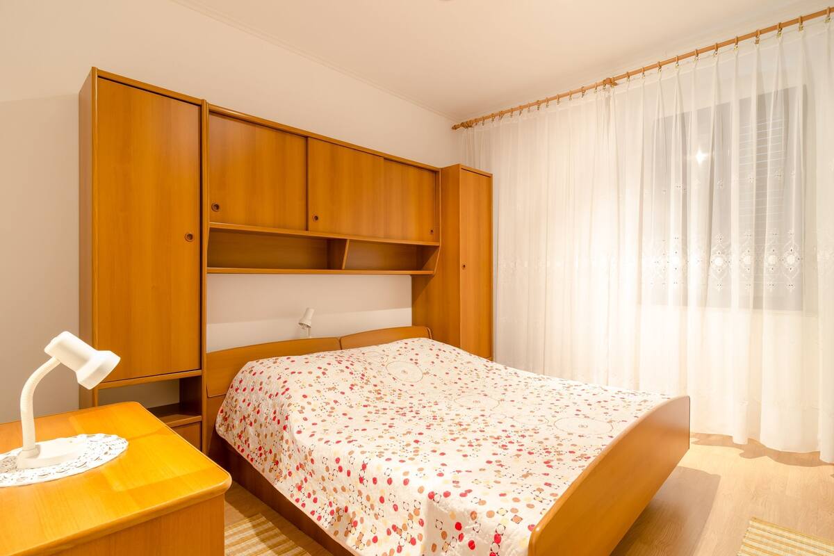 A bedroom with a wooden bed, a nightstand with a lamp, and a large wardrobe.