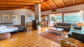 Un salón espacioso con suelo de madera, un sofá, una mesa de centro y una cama.