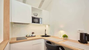 Una cocina compacta con microondas, lavamanos y una pequeña planta.