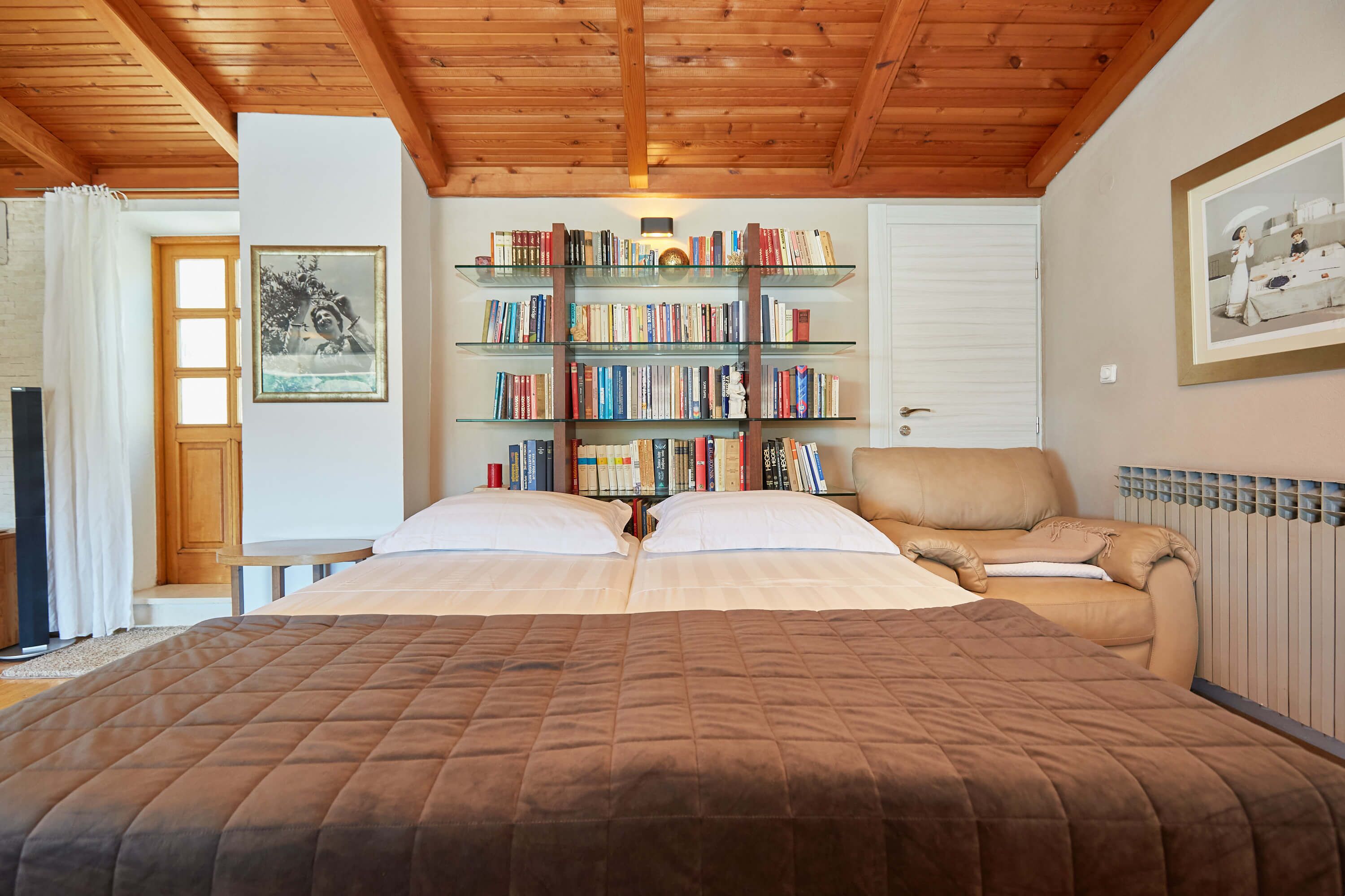 Un dormitorio con una cama grande, una estantería, una silla y un cuadro en la pared.