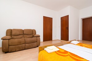 Un dormitorio con una cama, un sofá marrón y dos puertas de madera.