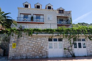 Un edificio de dos pisos con fachada de piedra, balcones con barandillas blancas y un letrero que indica un mercado.