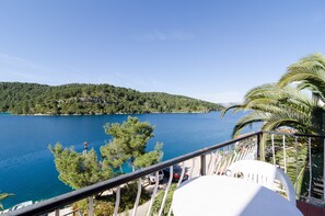 Un balcón con vista a un lago y una colina boscosa.