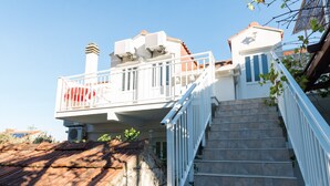 A residential building with a balcony, a staircase, and a tiled roof. - Guest House Matana Pomena (Mljet)
