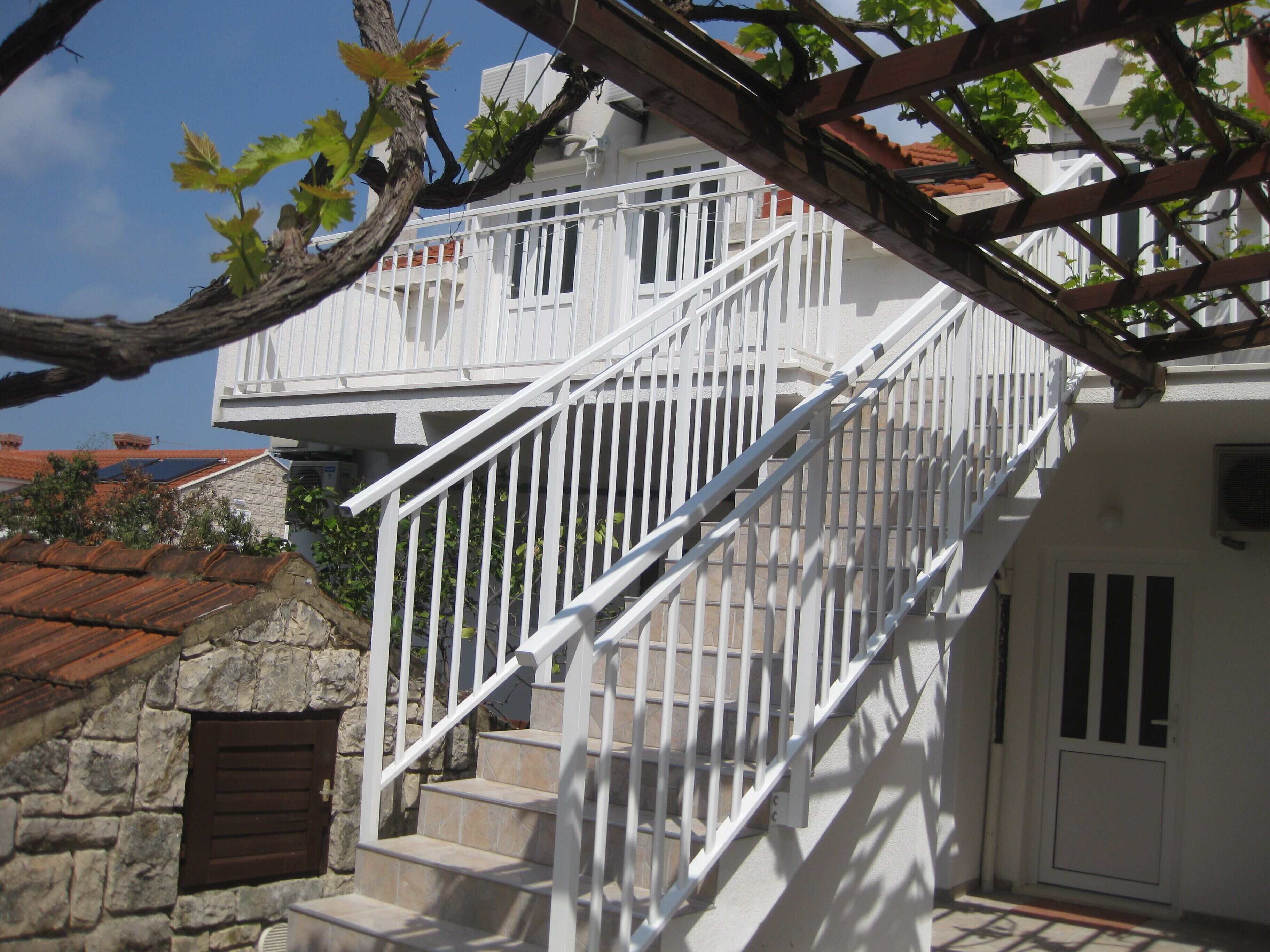 Una escalera blanca con barandillas de metal que lleva a un balcón.