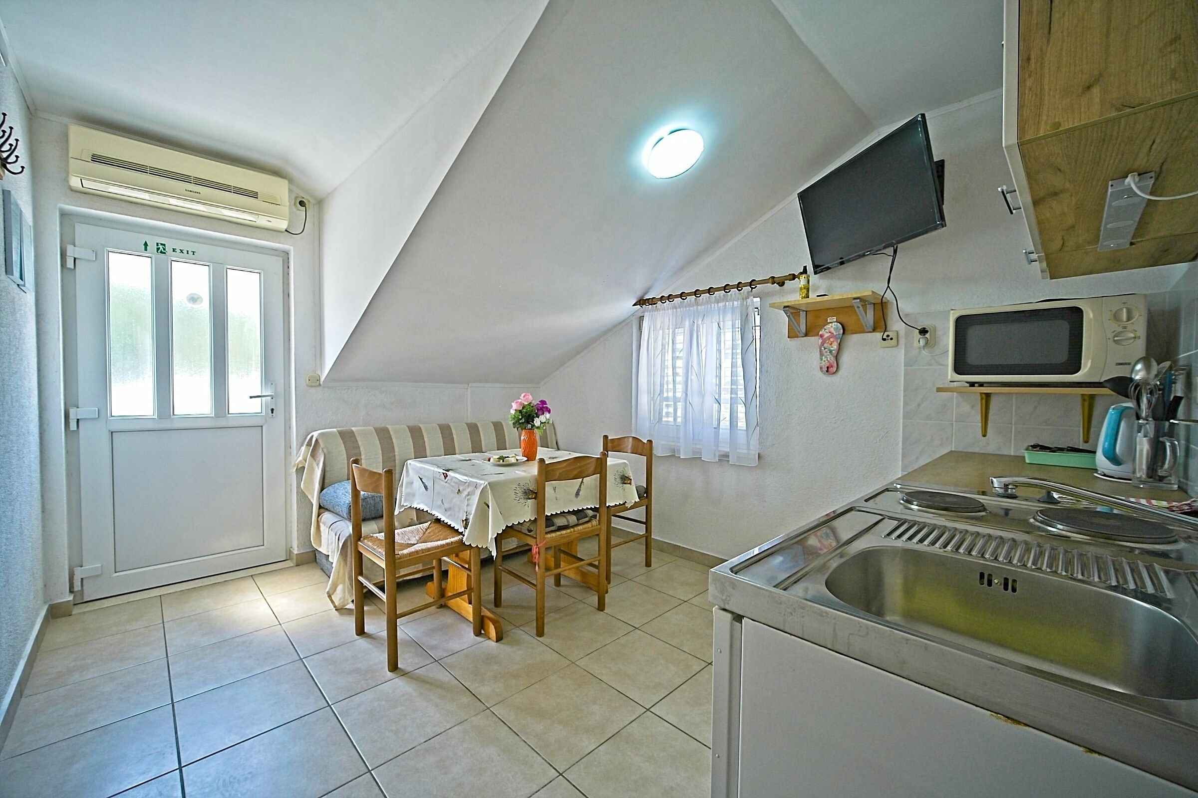 Una cocina compacta con microondas, fregadero y un rincón comedor con mesa y sillas.