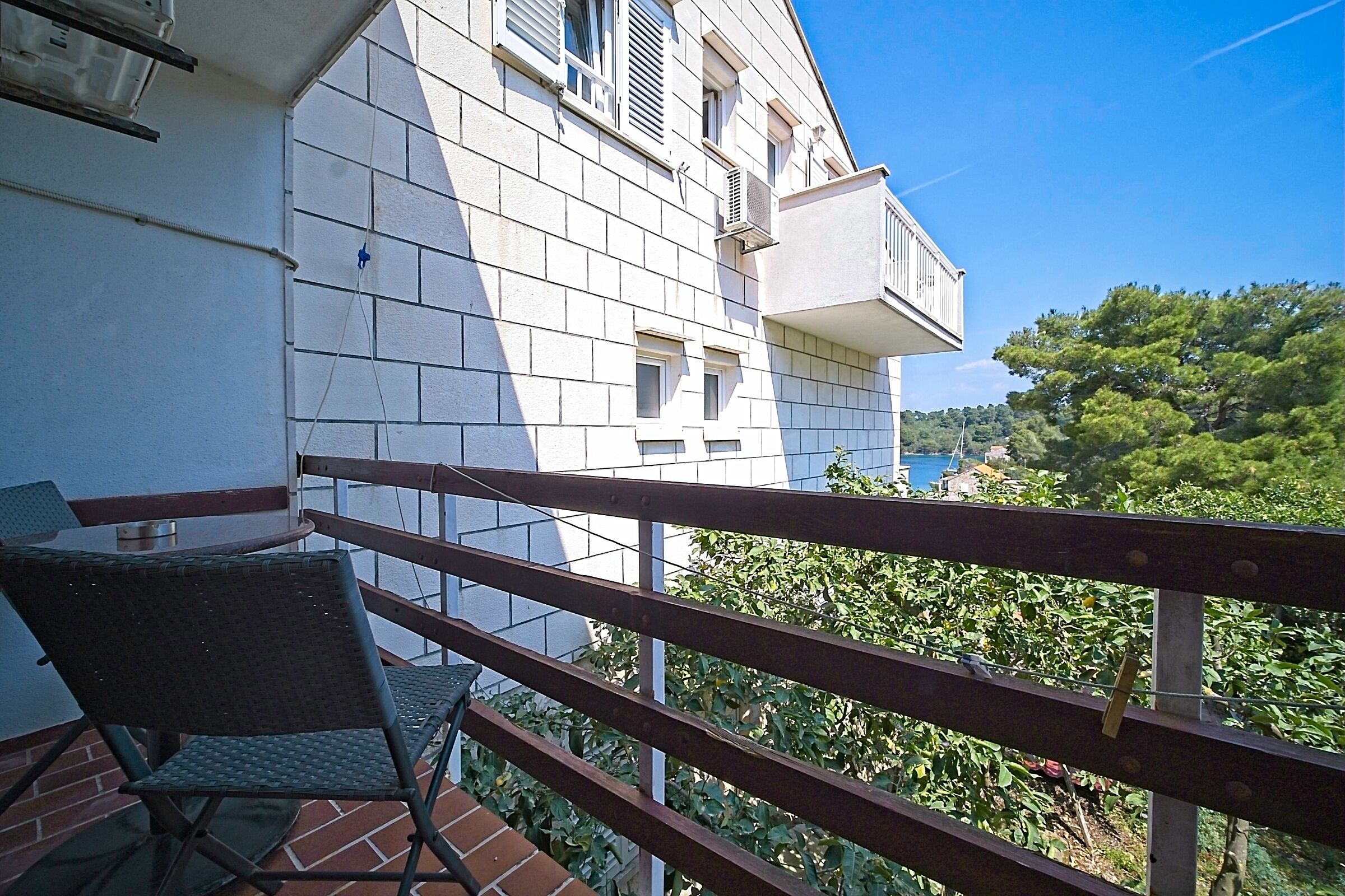 A balcony with a wooden railing, a folding chair, and a table.