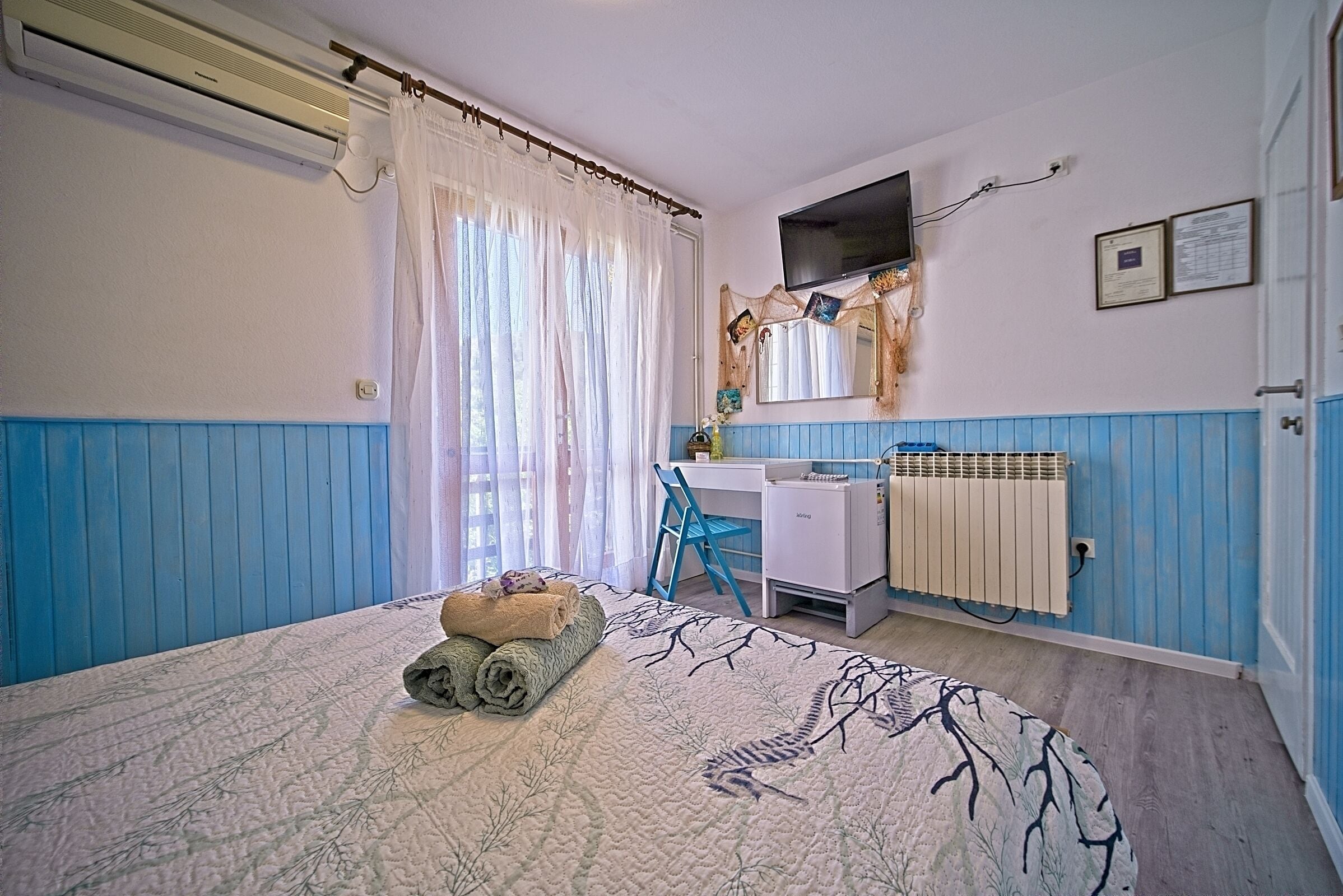 Een slaapkamer met een bed, een bureau, een stoel en een radiator.