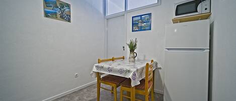 Una cocina pequeña con una mesa de comedor, sillas, un refrigerador y un microondas.