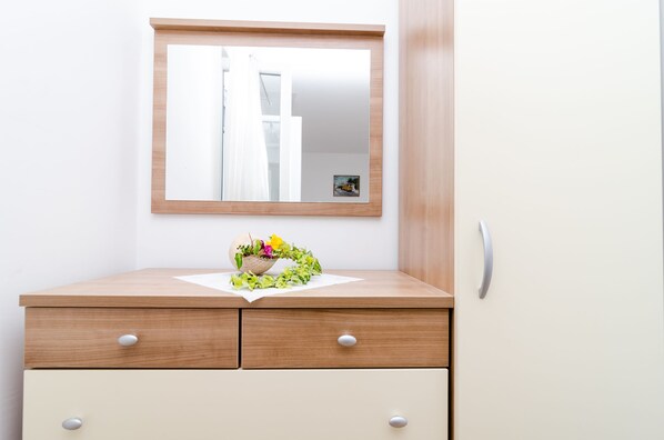 A wooden vanity with a mirror, two drawers, and a small potted plant on the countertop. - Rooms Karla (Mljet)