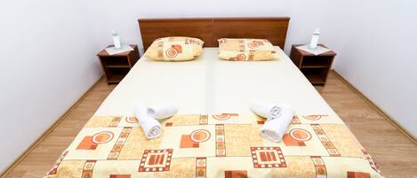 A neatly made bed with a patterned bedspread, two pillows, and two bedside tables with lamps.