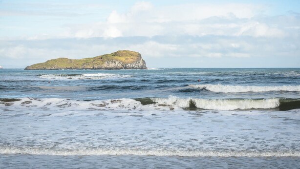 A coastal scene with a small island and waves approaching the shore. - Cosy Rest (North Berwick)