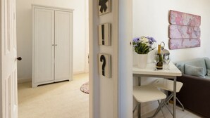 A room with a white wardrobe, a table with a vase of flowers, a bottle of champagne, and a world map artwork on the wall. - Cosy Rest (North Berwick)