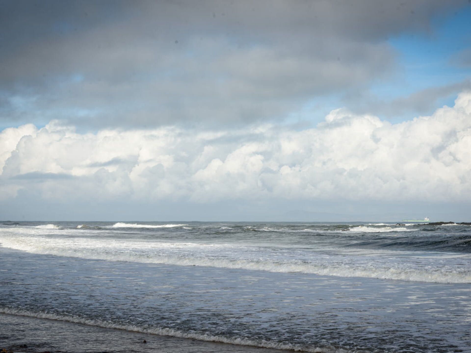 A beach with waves and a cloudy sky.