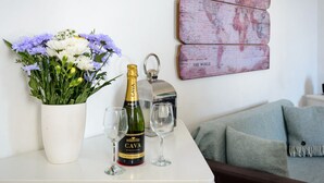 A table with a bottle of CAVA, two wine glasses, and a vase of flowers. - Cosy Rest (North Berwick)