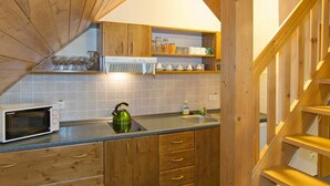 A kitchen with wooden cabinets, a microwave, a kettle, and a sink.