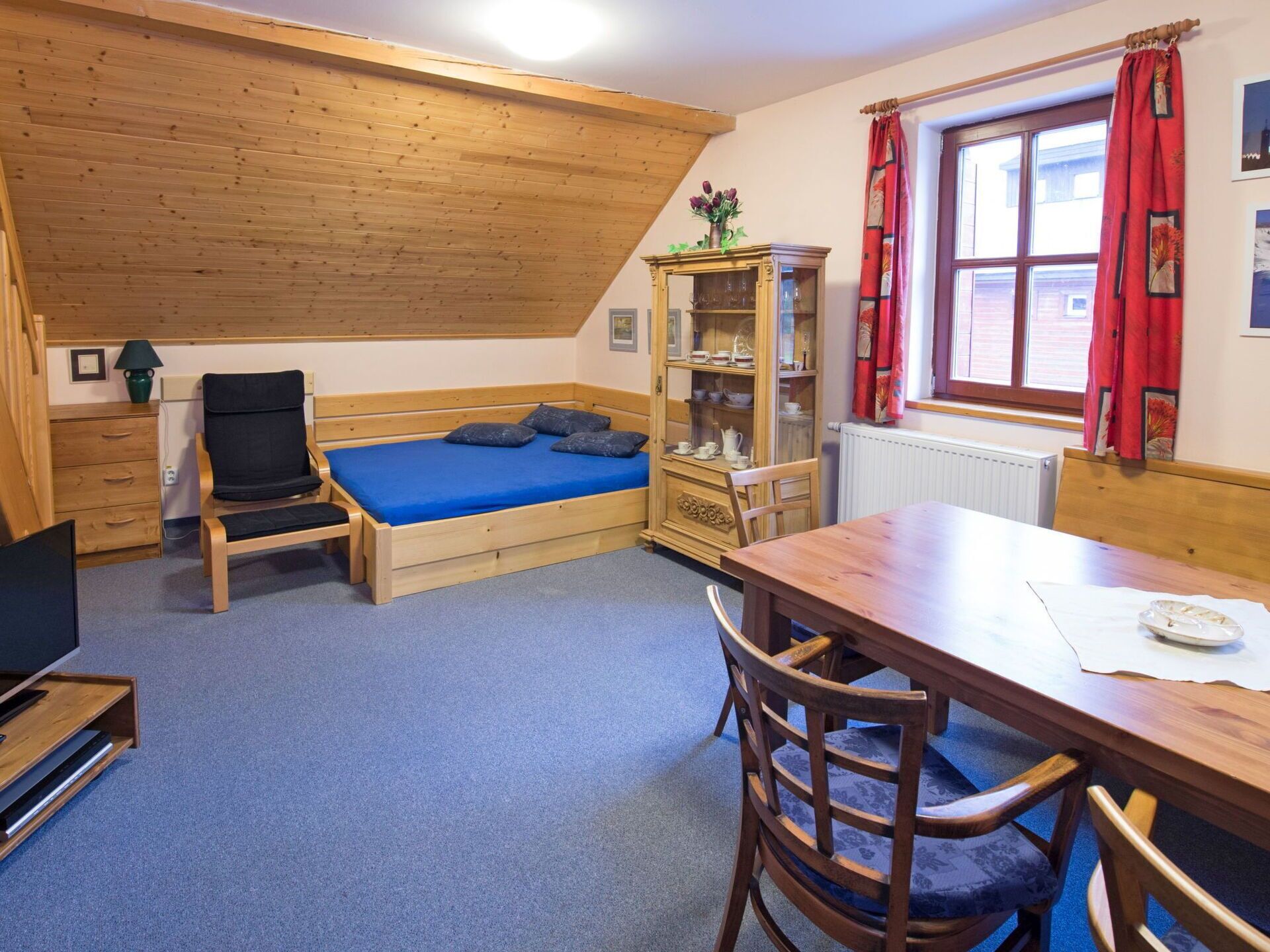 A small, cozy room with a wooden bed, a desk, a chair, and a cabinet.